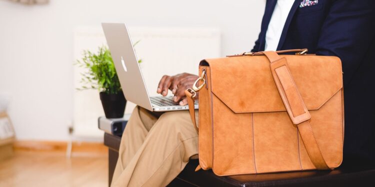A man in a suit sitting on a couch with a laptop. - mybiked.com